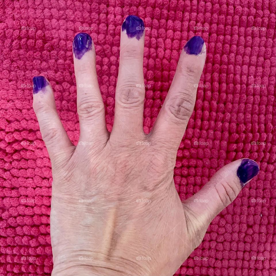 Woman’s hand with brightly colored messy nail polish, child paints mother’s nails a bright purple, color explosion on your nails