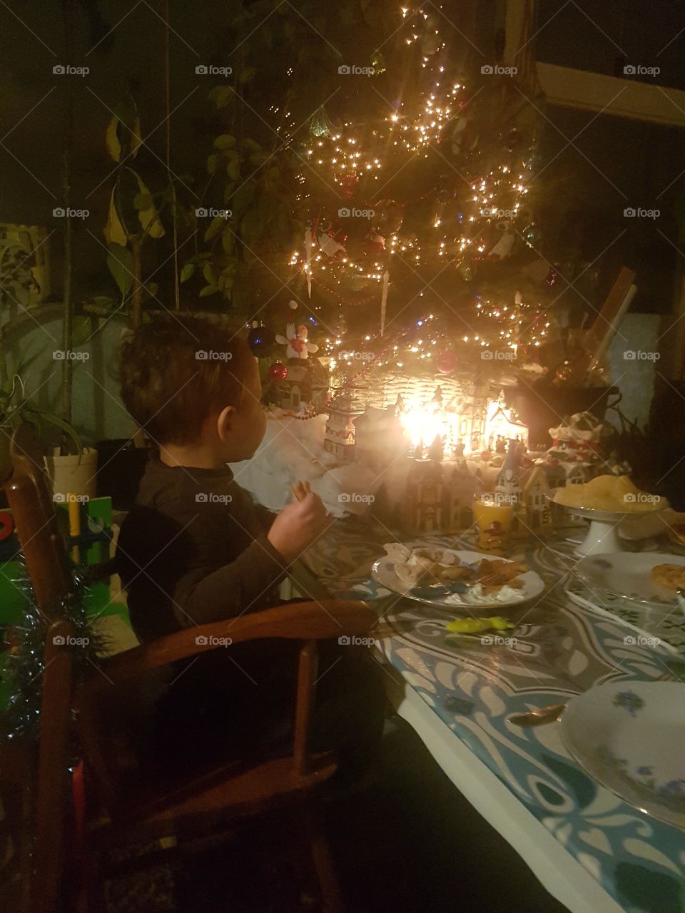 Christmas diner. tree lights food people family eat eating child boy