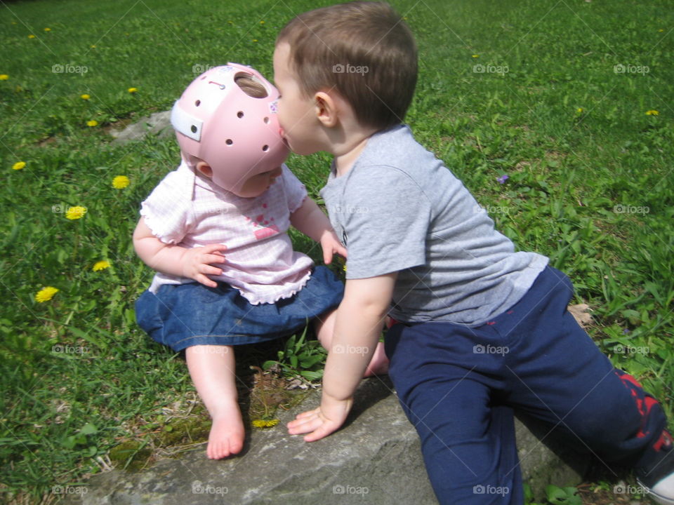 Toddler boy kissing his little baby girl