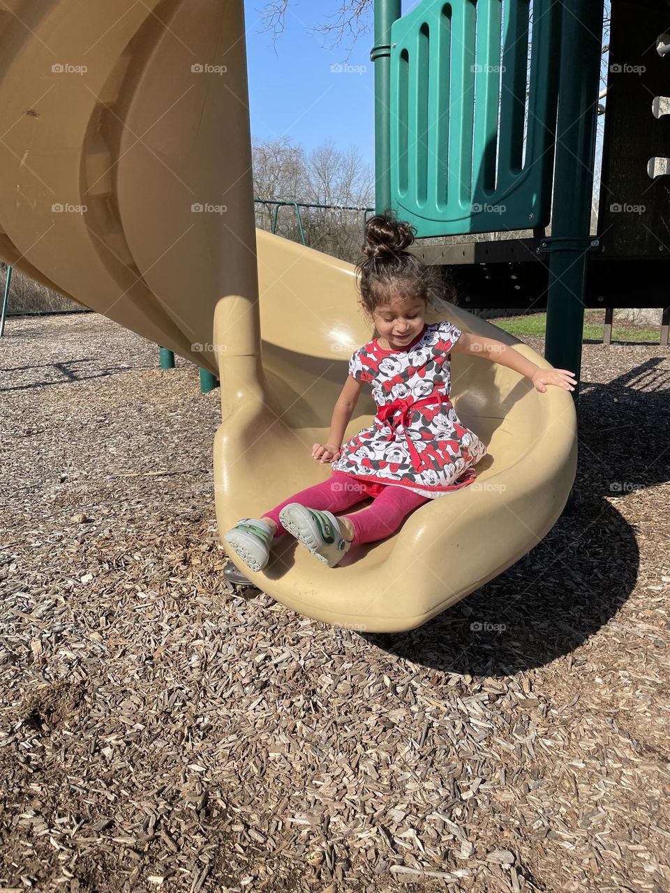 Toddler girl comes down the slide at the park, playing at the playground, toddlers in motion, children playing outside, going down the slide, toddler girl plays outside 