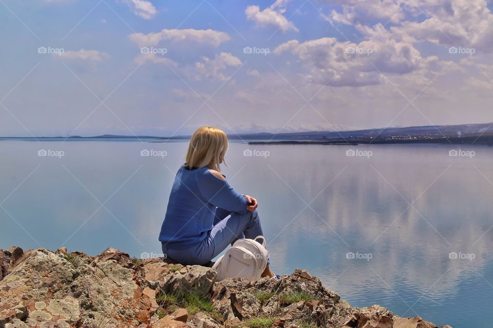 blonde girl sitting by the lake