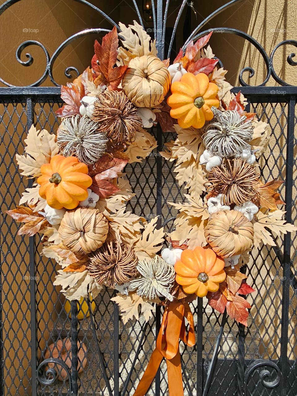 Beautiful fall wreath adorning the front gate to a home in San Francisco California with pumpkins and fall colored leaves 