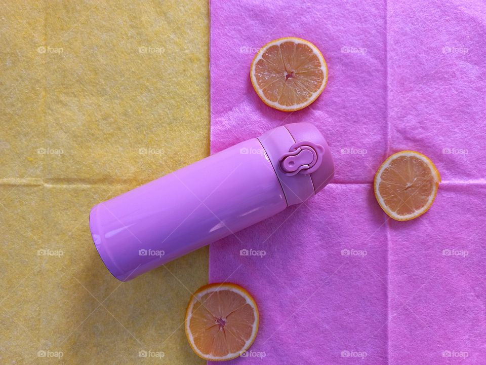 a combination of pink and a yellow-pink thermo mug on the background of a yellow napkin and slices of yellow lemon on the background of a pink napkin!