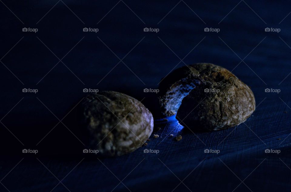 Two cookies in the dark one of which is broken and mysterious blue light pours from the cookie of the cookie