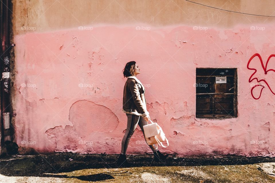 Girl with a pink backpack is walking near pink wall, going from A to B be feet 