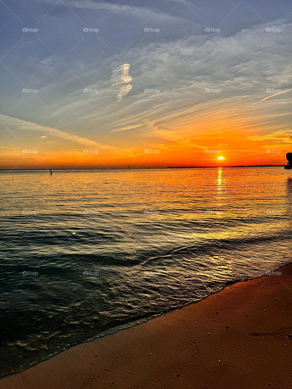 The beautiful sunset at Key Colony beach where the waves gently roll up the shore as a crowd of people sing their nightly song at sunset at this great location in Marathon, Florida 