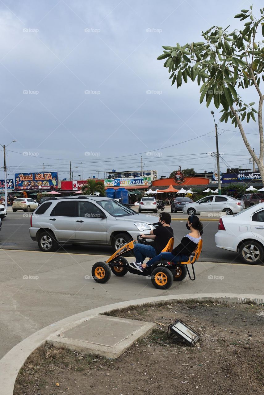 Two people on a four-wheeled tricycle ride.