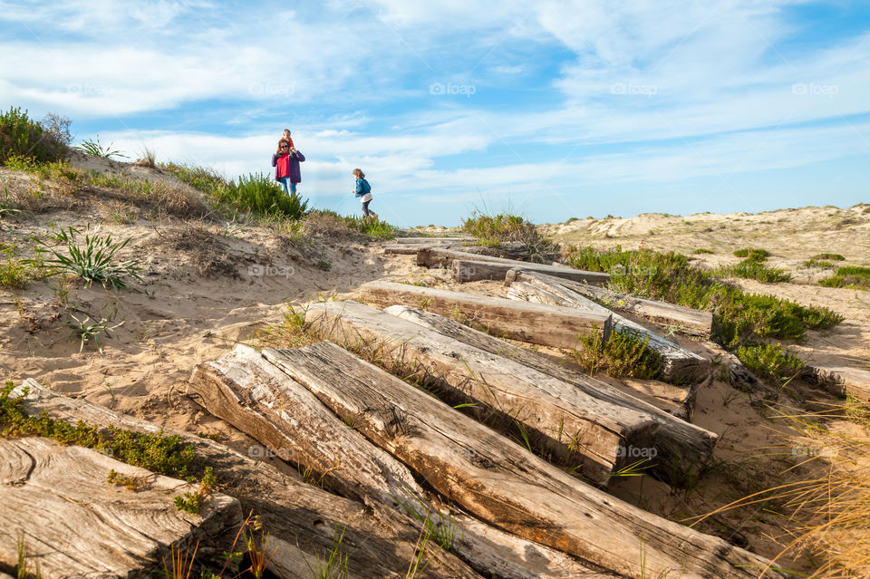 Family day out at coastal sand dunes. Derelict railway sleepers footpath.