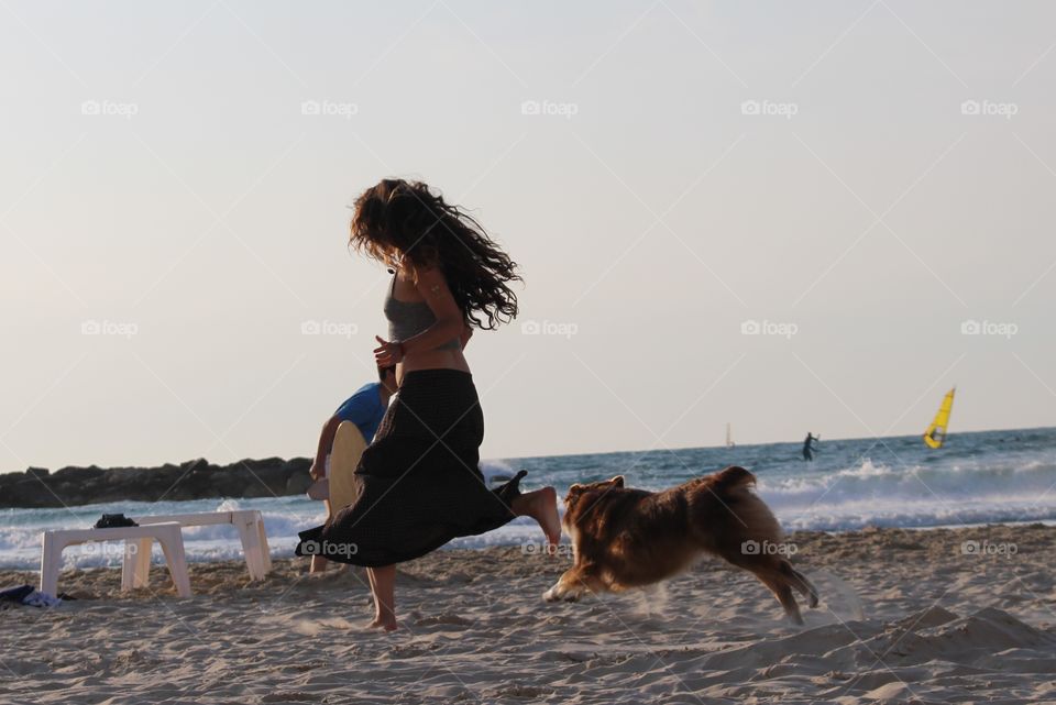 Woman running on beach with dog