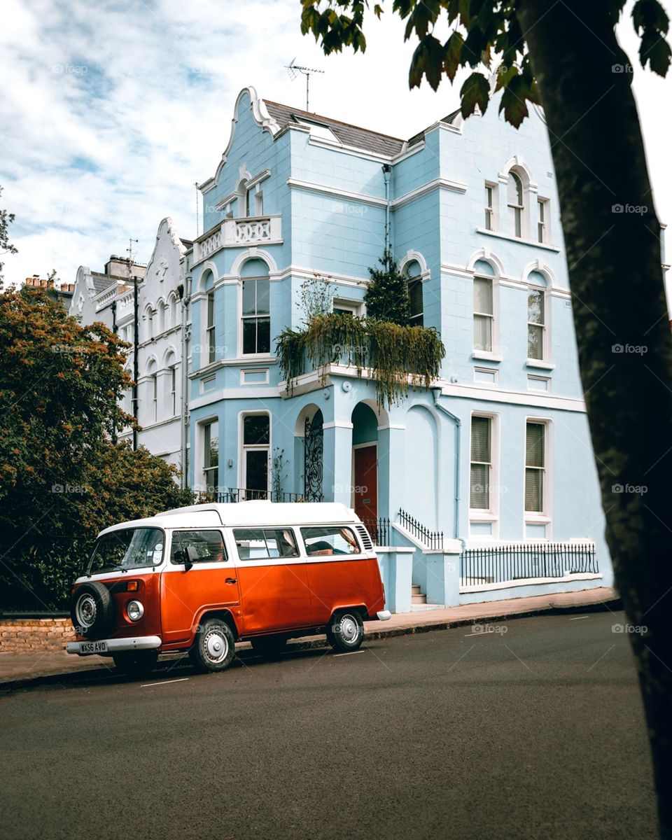 An old bus in front of a blue house 