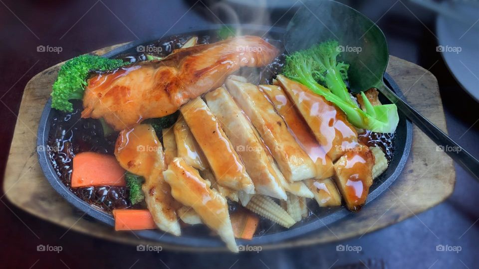Salmon and chicken teriyaki combo on the sizzling plate served ready for dinner. 