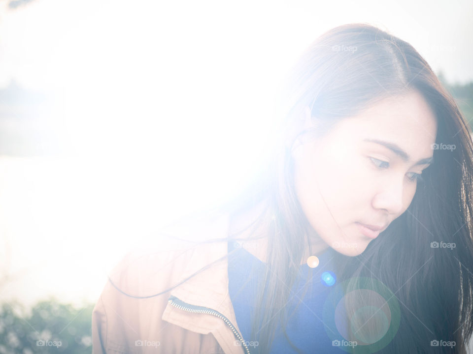 Girl looking down with sun flare from behind