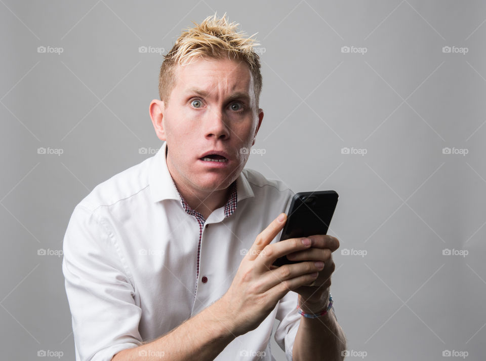 Surprised and sad man with cellular phone.