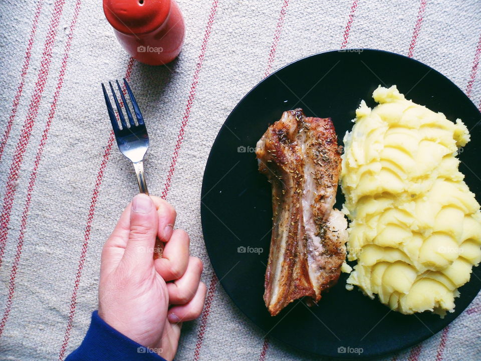 grilled pork ribs, potato puree on a black plate