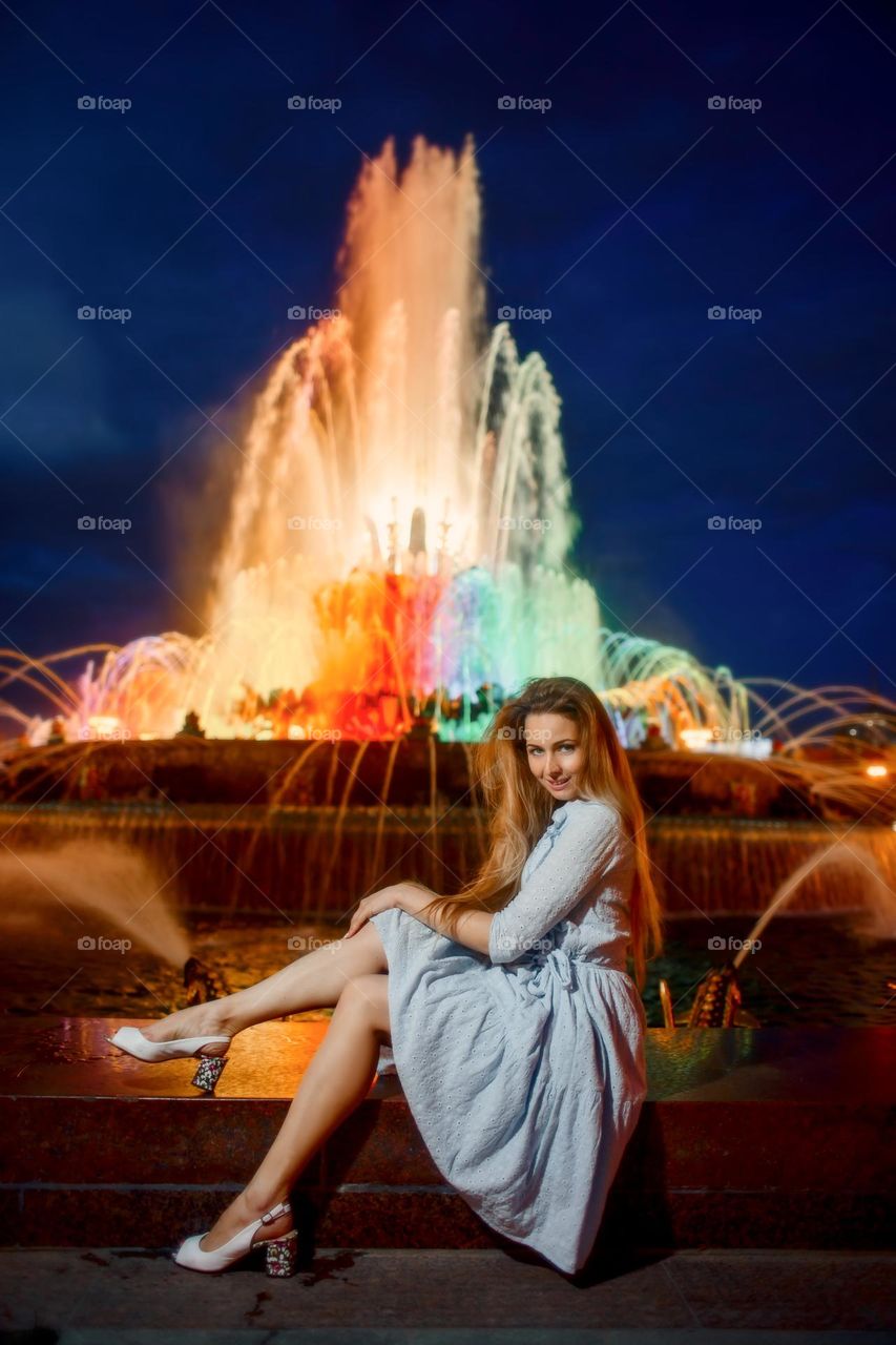 Young woman near colourful fountain