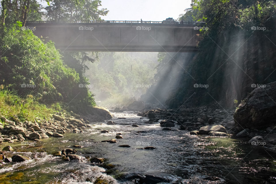 Sunrays falling over the mossy stones on a river.