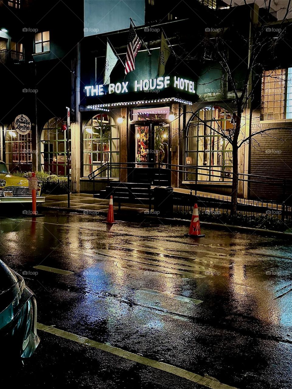 This elegant nighttime view is the “THE BOX HOUSE HOTEL”. It occupies a five story building on “Box St” in “Greenpoint”, Bklyn that extends over nearly an entire city block. The lobby lights reflect in the wet rainy street. 2023. Hypnotic Productions