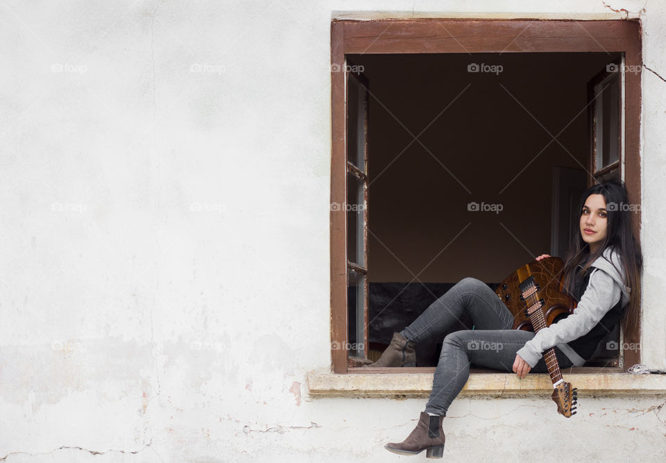 A woman with guitar on the window