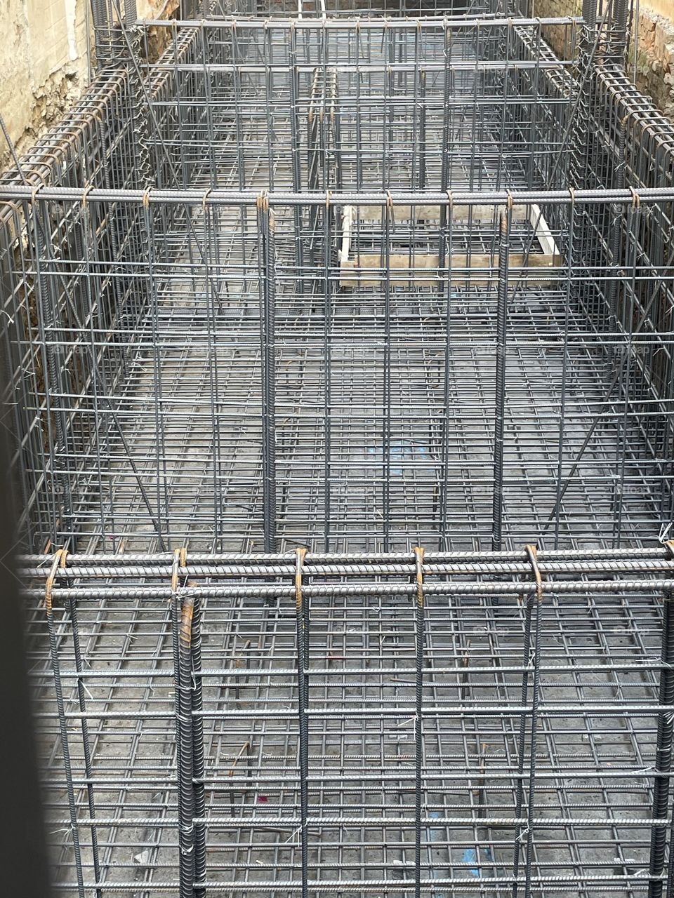 The metal foundation at a construction site. There are several intricate, metal bars. Photo taken during daytime. 