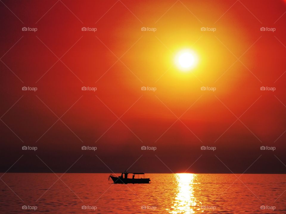 Sunset over sea with silhouetted boat