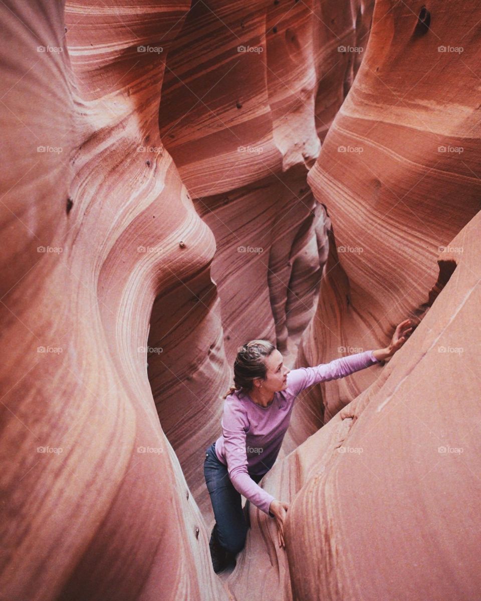 Girl rock climbing through slot canyon in Arizona pink colorful fun outdoor adventure travel sandstone layers explore one person pretty landscape rock