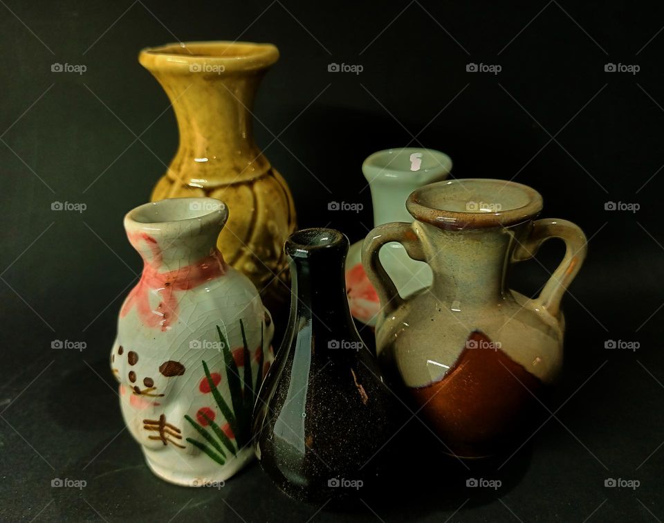 Still life with Variations of earhenware Pot and bottles isolated on black background