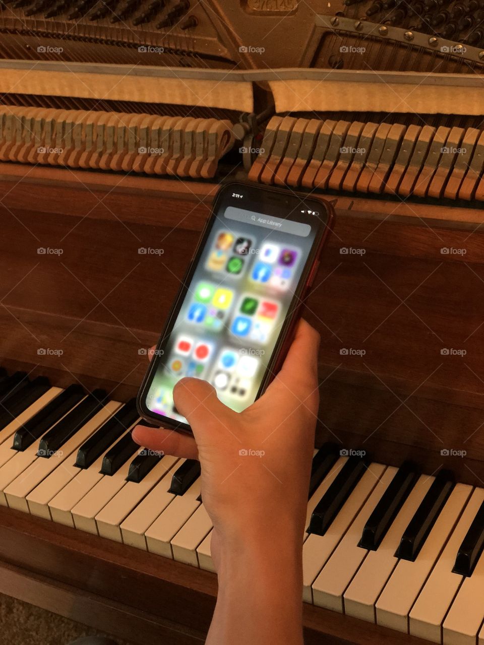 Music student working from home, using iPhone it at the piano