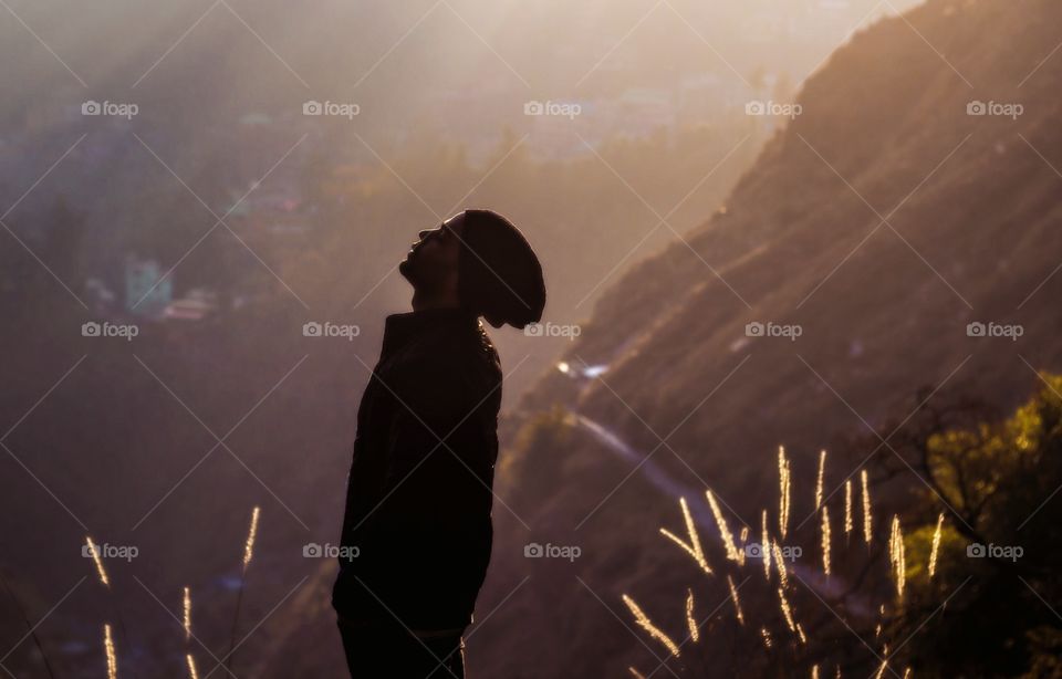 Young man standing near mountain during sunrise