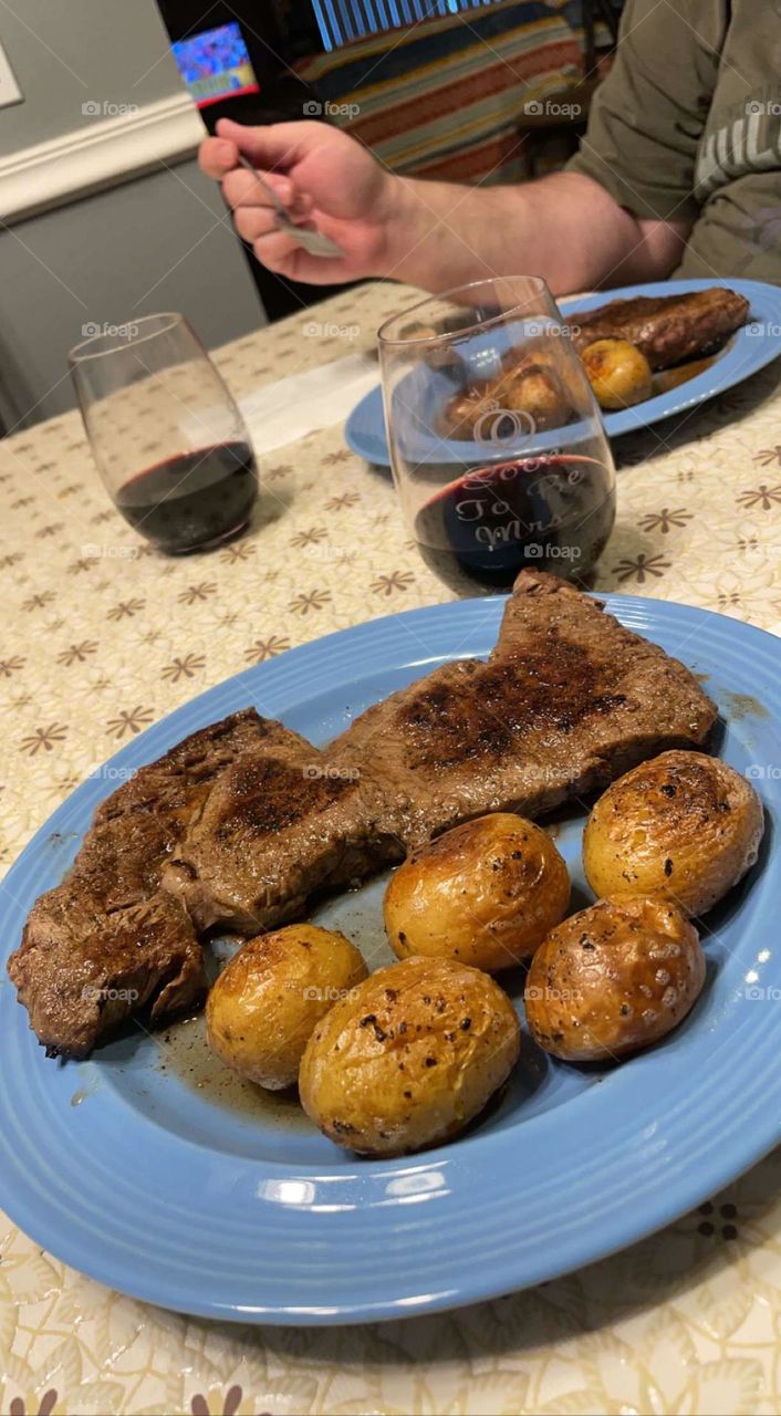 A romantic and delicious dinner of ribeye steak, roasted potatoes with rosemary, and red wine