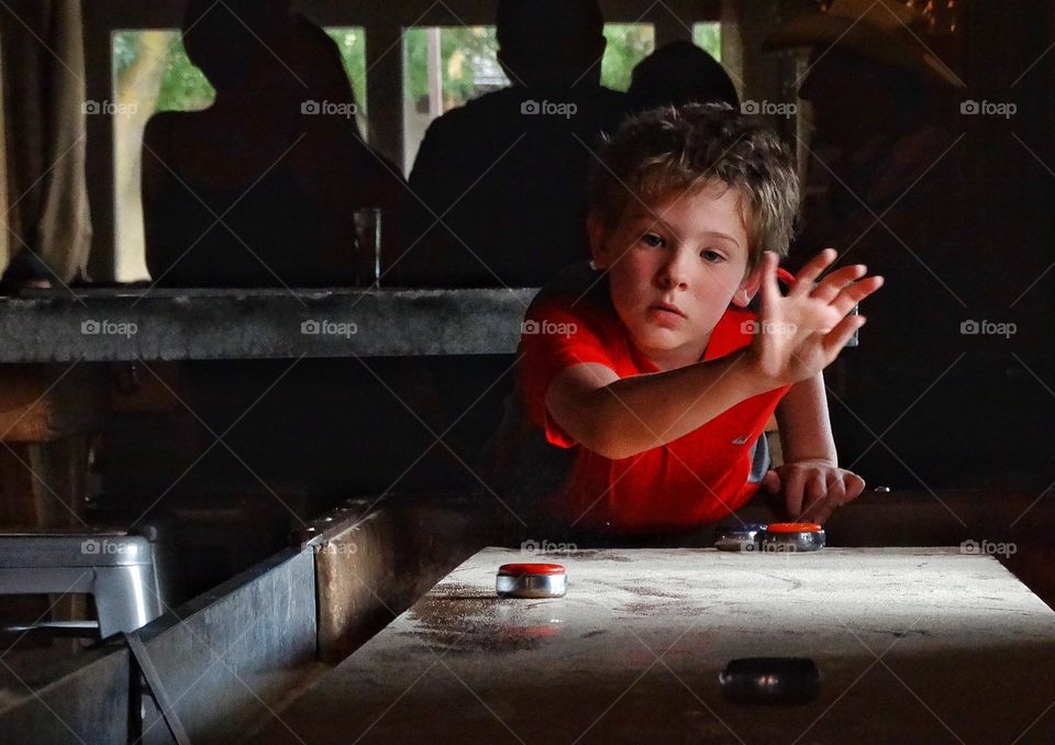 Playing Shuffleboard. Boy Playing Indoor Shuffleboard
