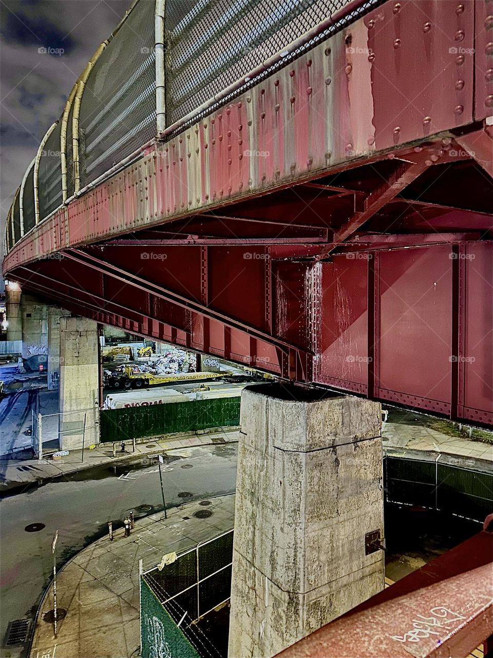 This utopian structure of modern architecture is the red metal underside with support beams of the „Pulaski Bridge“ at „Newtown Creek“ on the „Greenpoint“, Brooklyn side of the bridge on a chilly evening in late December 2023. Hypnotic Productions