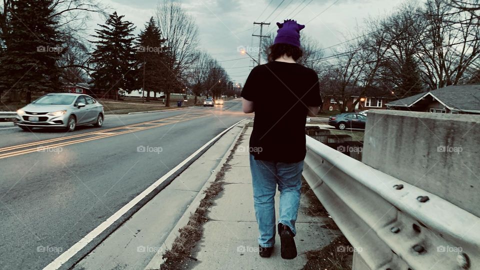 A young man on his daily evening walk. It’s an unusually warm winter night, walking over the city bridge. 