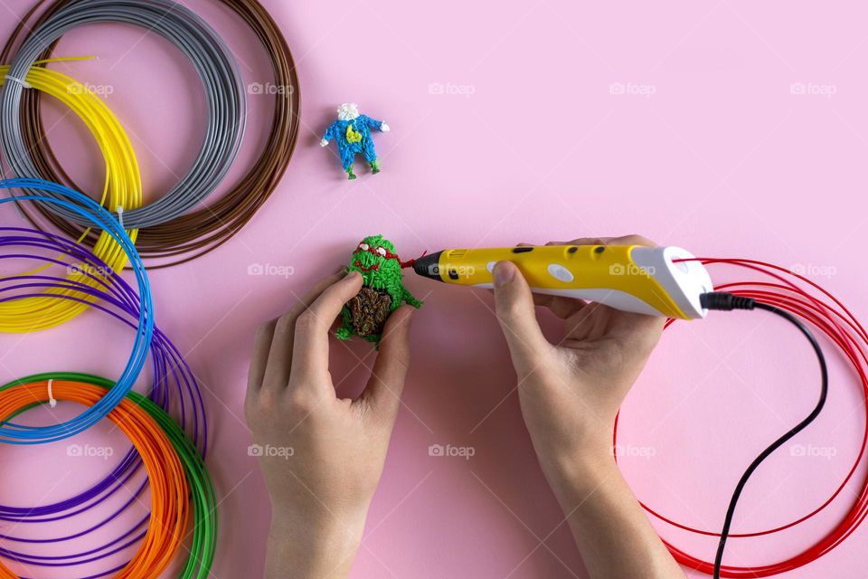 Hands with 3d pen create 3d figures from plastic 