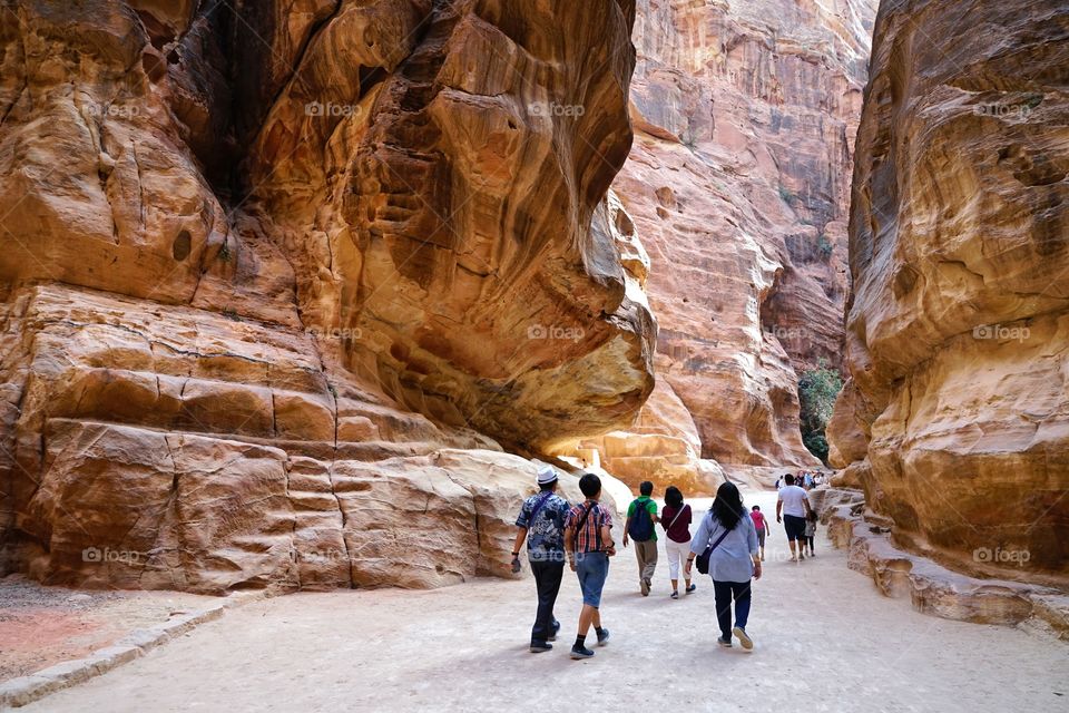 group of tourists walk thru the canyon of Petra of Jordan