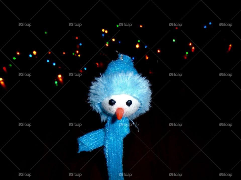 Toy snowman for Christmas decoration with lights in the background