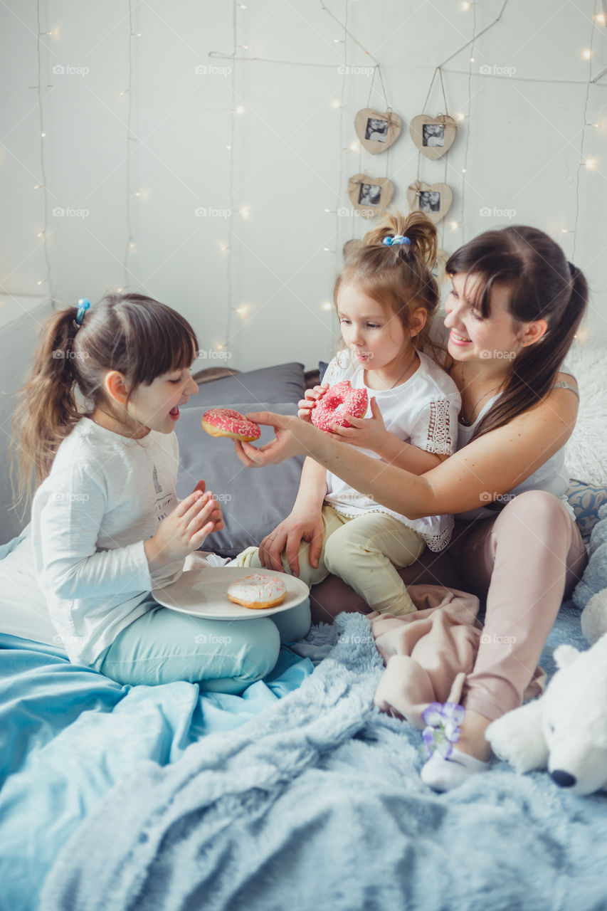 Happy family, mother and daughters with donuts 