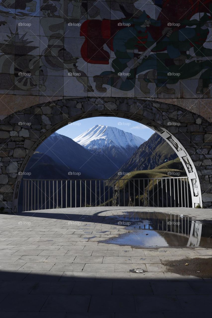 Snowy mountain peak through the Arc of Friendship in Georgia