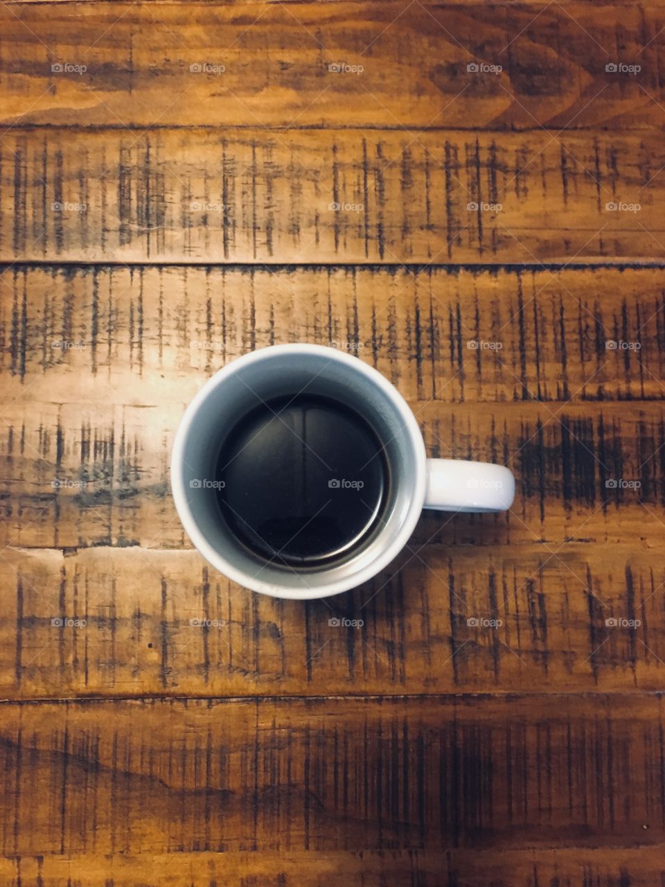 Black coffee in a mug on a pine wood table in the morning 