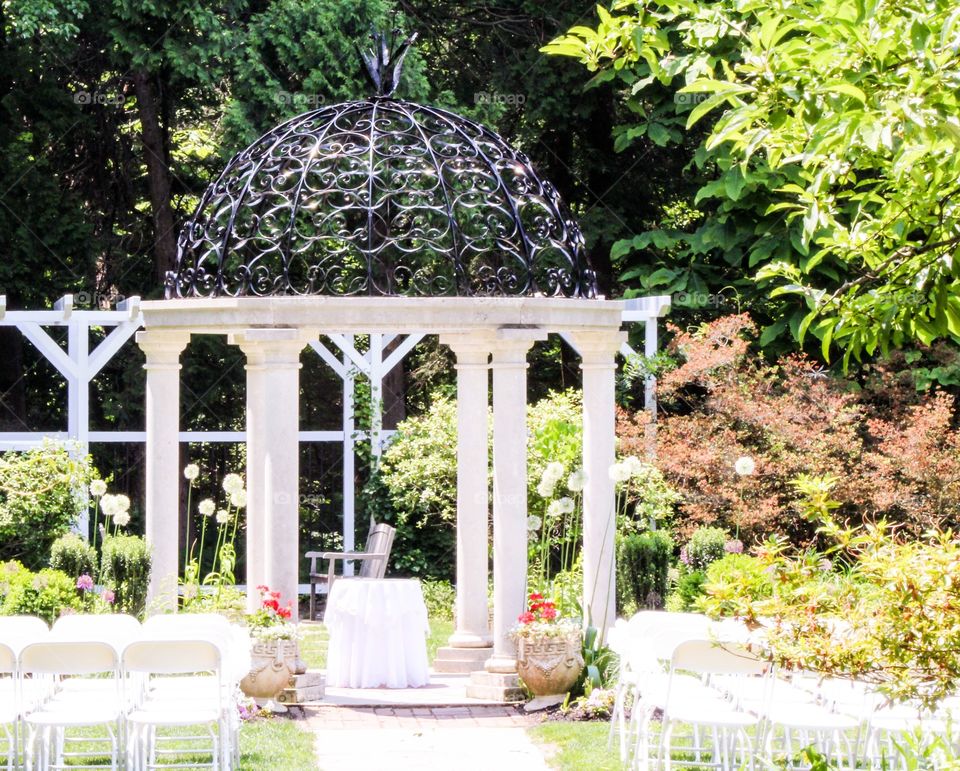 A wedding setting in the garden. Taken in a garden with lots of flowers. This is the before any of the ceremony takes place. There is a bright light hearted wedding setting.