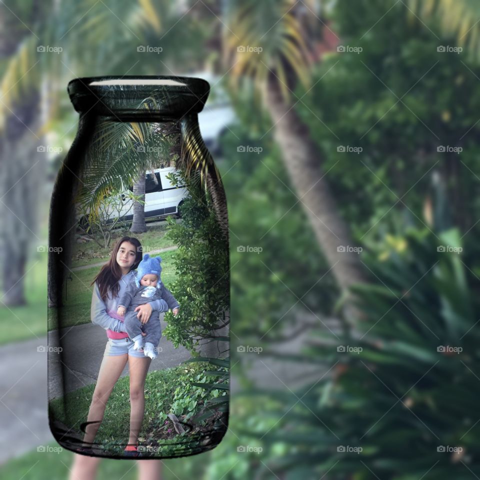 Transparent bottle in front of girl carrying baby
