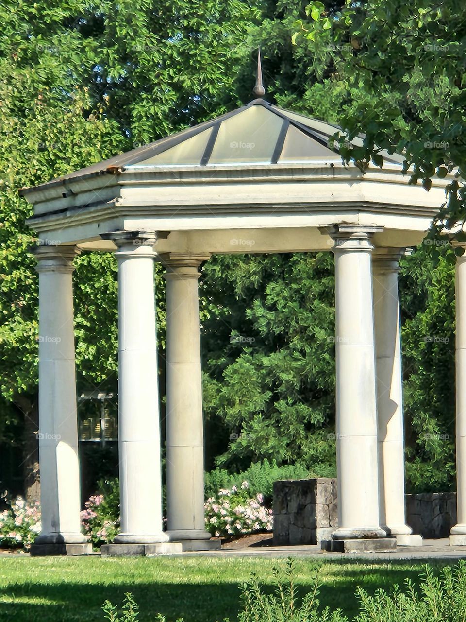 this charming white pavilion surrounded by green trees in an Oregon park provides shade and rest on a sunny day