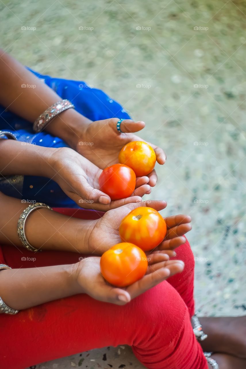 Girls holding tomatoes in hand