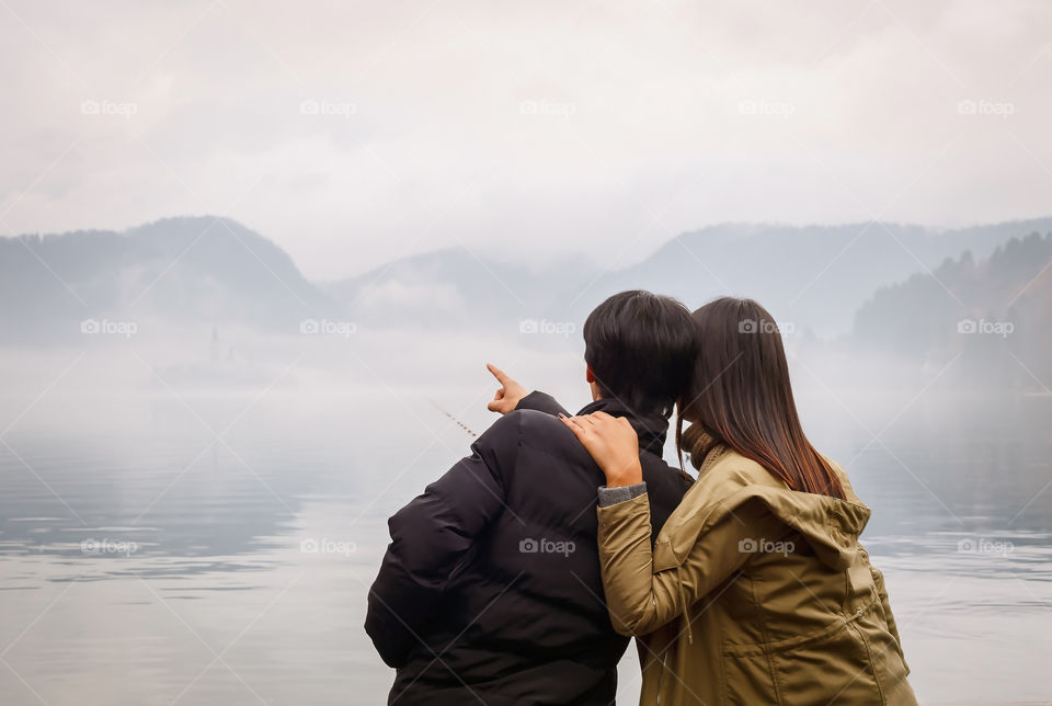 Young couple enjoying view of foggy lake in winter
