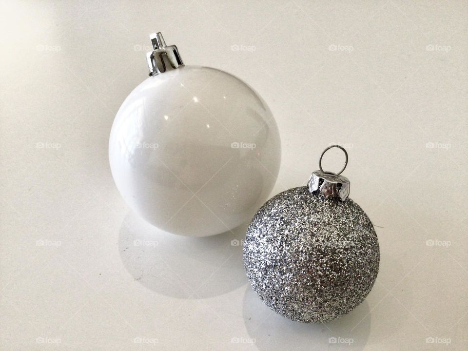 Christmas baubles shining on a cleaned white table, the November morning sun shining onto the reflective one and bouncing off the glittery one.