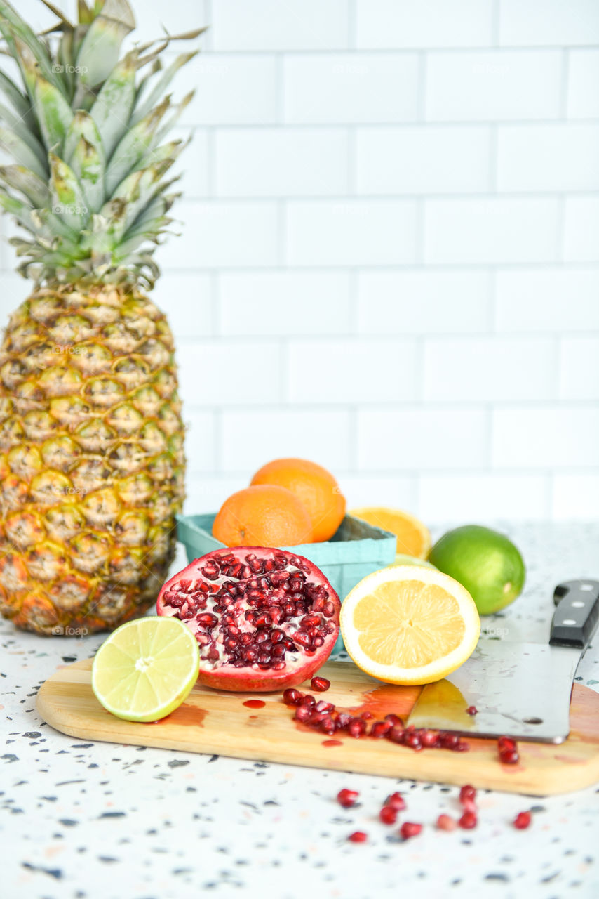 Close-up of an assortment of fruit on a kitchen countertop with a cutting board and cleaver