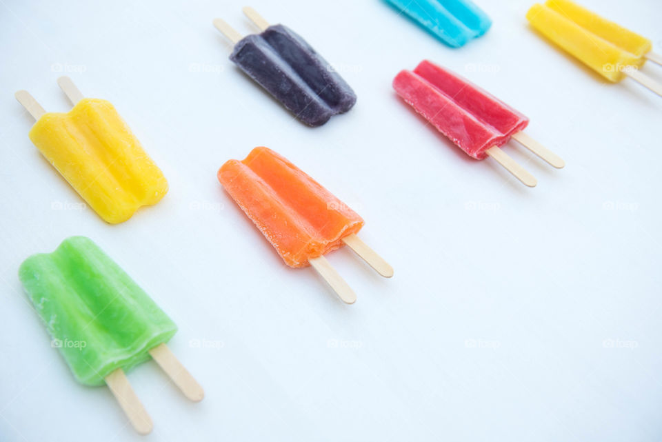 Isolated image of a row of brightly colored popsicles arranged in a pattern on a white background