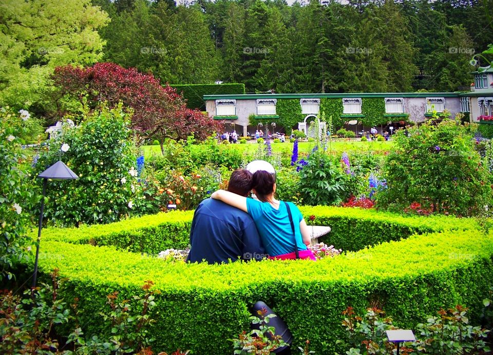 Sweethearts in the Butchart gardens in Victoria in British Columbia, Canada. Couple, hug, embrace, floral, summer