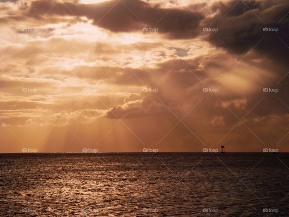 sunset at sea with ship. while sailing I saw this beautiful sun though the clouds with a ship on the horizon