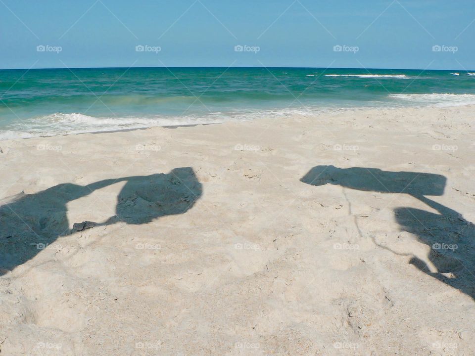 Bodyboard for body surfing showing the shadow of the excited children before they jump in the Atlantic Ocean in Florida with shadow of them holding their surf board in the air.