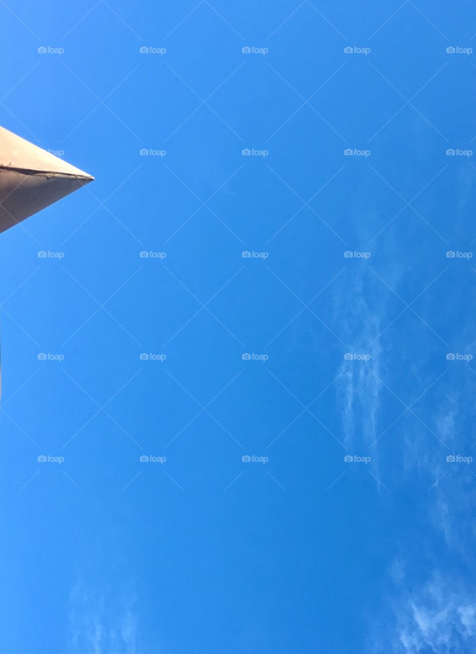 Cone shaped tin triangle structure pointing into blue sky minimalist image 